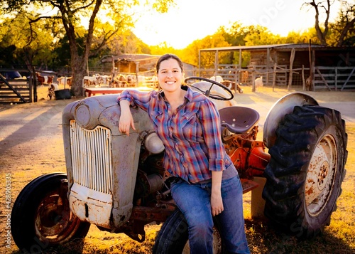 Farm girl on tractor at sunset photo