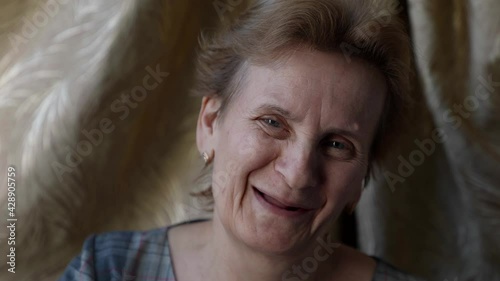 cute old woman with toothless smile is looking at camera, closeup portrait indoors
