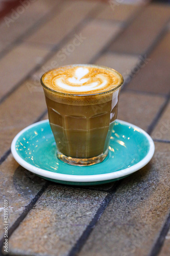 decorated glass of Coffee Piccolo Latte on a white table in a Sydney Cafe NSW Australia
