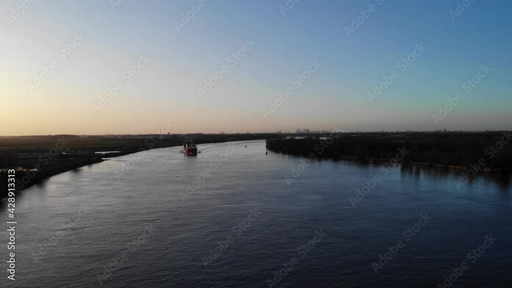 Approaching Trading Vessel Slowly Traveling On Oude Maas River At Dusk In South Holland, Netherlands. - Aerial Shot Approaching Trading Vessel Slowly Traveling On Oude Maas River At Dusk In South Holland, Netherlands. - Aerial Shot