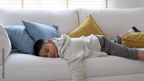 Fatigue in children laying fall down asleep slumber on sofa at home need rest or brain break after virtual study online remote learn at home problem in asian kid feel lack of energy and tired.