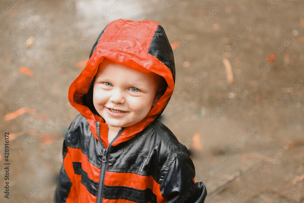 Beautiful little toddler boy wearing red coat while playing in the rain Beautiful little toddler boy wearing red coat while playing in the rain