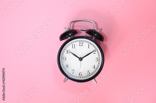 Black vinatge alarm clock with pink background.