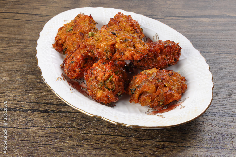 Fototapeta premium Deep fried piaju onion fitter bhajia on decorated ceramic plate over rustic wooden background