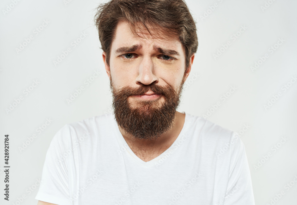 Bearded man in a white T-shirt on a light background sad face emotions beard Bearded man in a white T-shirt on a light background sad face emotions beard