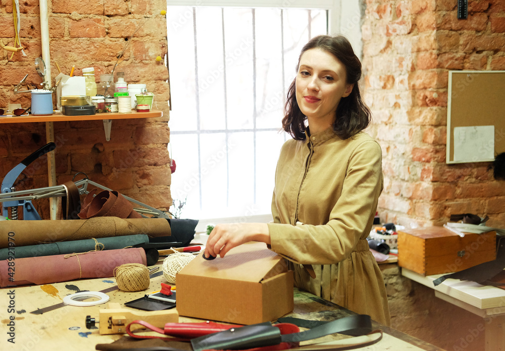 brunette woman folds packing box in sewing workshop brunette woman folds packing box in sewing workshop