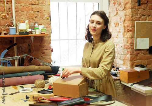 brunette woman folds packing box in sewing workshop