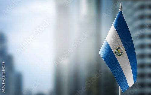 A small flag of Salvador on the background of a blurred background