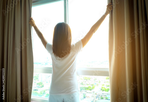 Free Download Morning of a new day, Women wake up from bed. In the morning, she opens the curtains in her bedroom for fresh air and natural morning sunshine. - GFXLoad