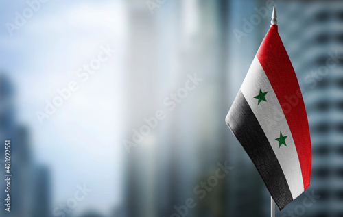 A small flag of Syria on the background of a blurred background