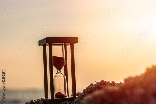 Time concept Hourglass on sandy beach in summer with sea background