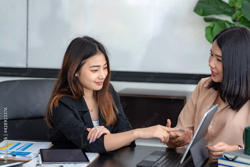 Two Asian businesswoman brainstorm work together using tablet at the office. Two Asian businesswoman brainstorm work together using tablet at the office.
