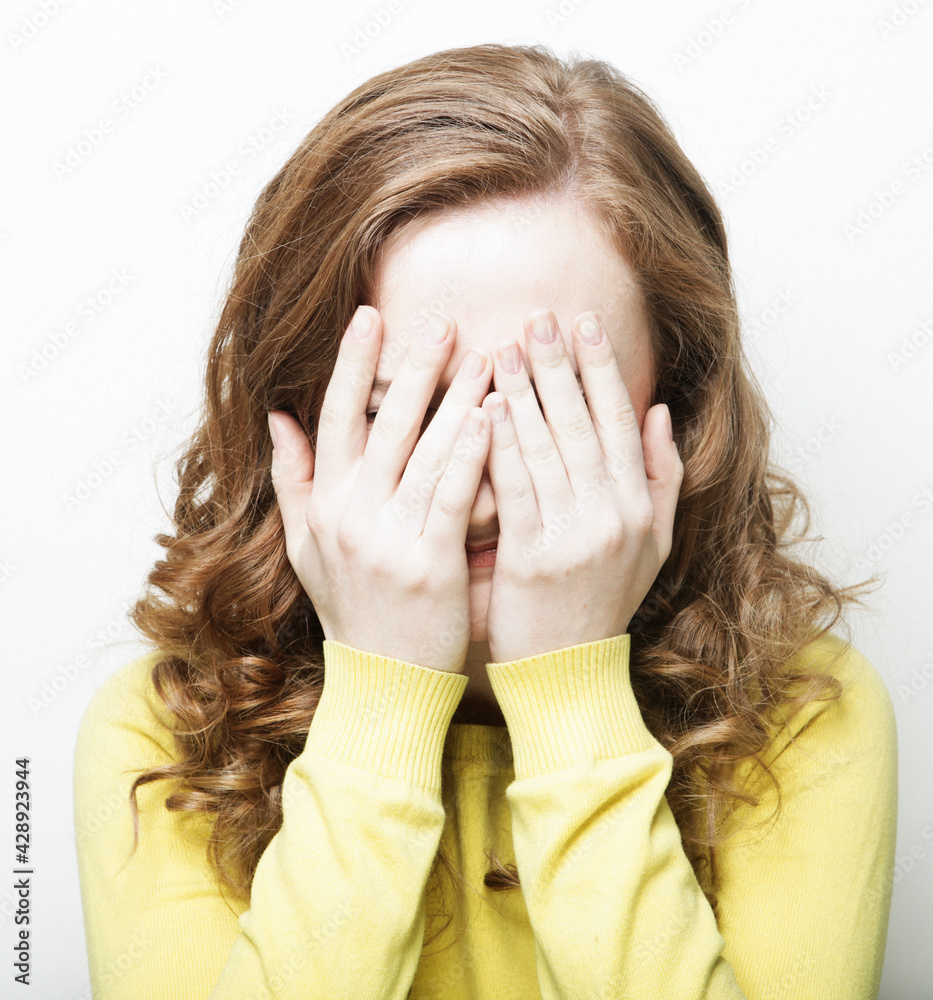 Emotion and people concept: Young blond woman covering her eyes over white background Emotion and people concept: Young blond woman covering her eyes over white background