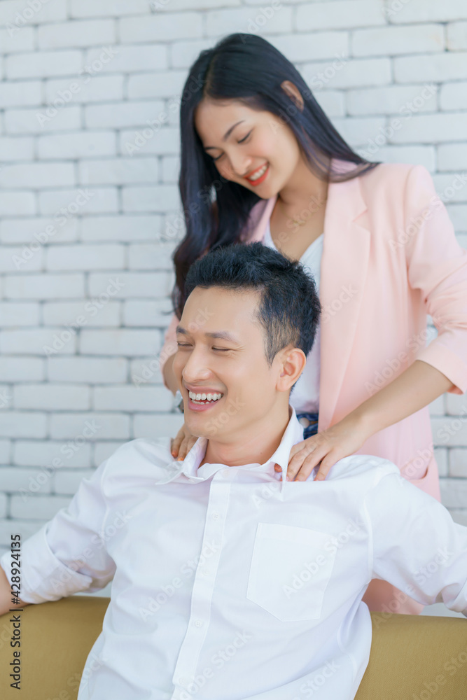 Happy couple Boyfriend sitting on sofa and Girlfriend is giving her shoulder massage after Business man working from home Happy couple Boyfriend sitting on sofa and Girlfriend is giving her shoulder massage after Business man working from home