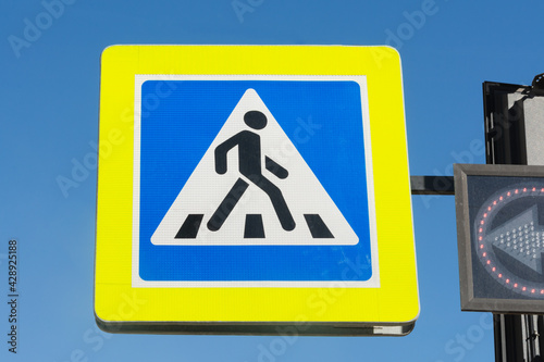 Pedestrian crossing sign on the street. Transition symbol. A person walks along the transition in a white triangle on a blue background with a yellow icon