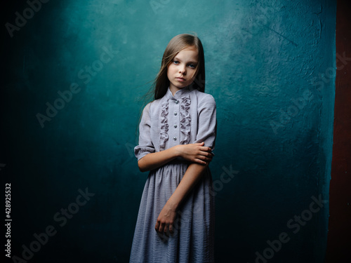 Pretty girl in a gray sundress with loose hair on a turquoise background