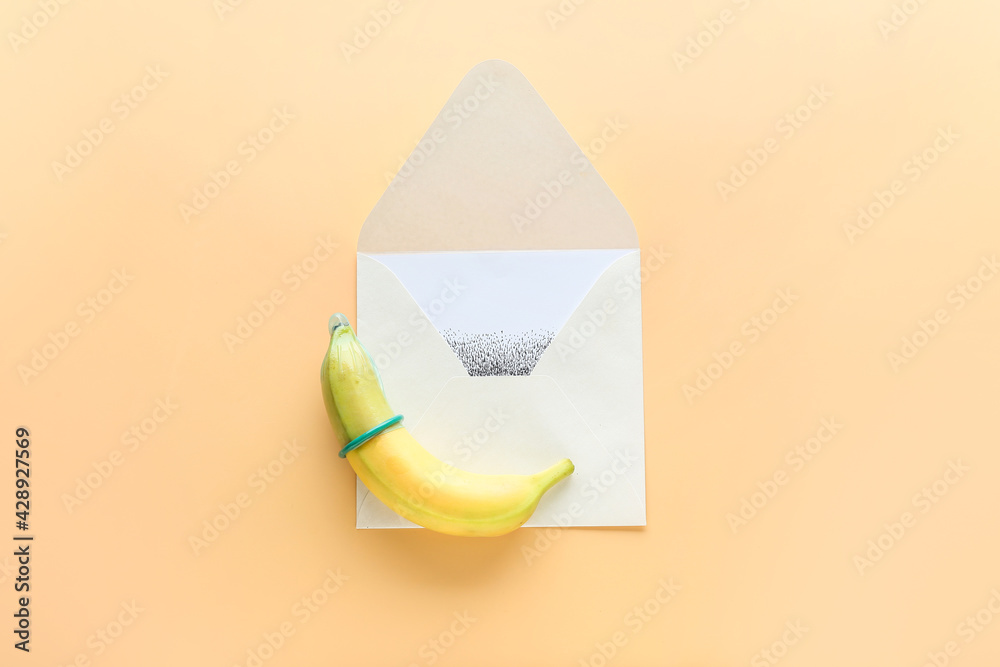 Banana with condom and open envelope on color background. Erotic concept Banana with condom and open envelope on color background. Erotic concept