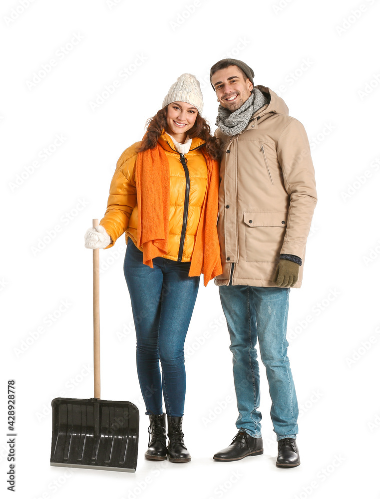Young couple with shovel for removing snow on white background