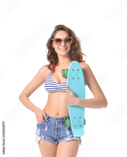 Beautiful young woman in beachwear and with skateboard on white background