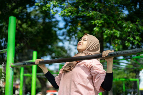 a girl in a veil does pull ups to work out her hand muscles in the park