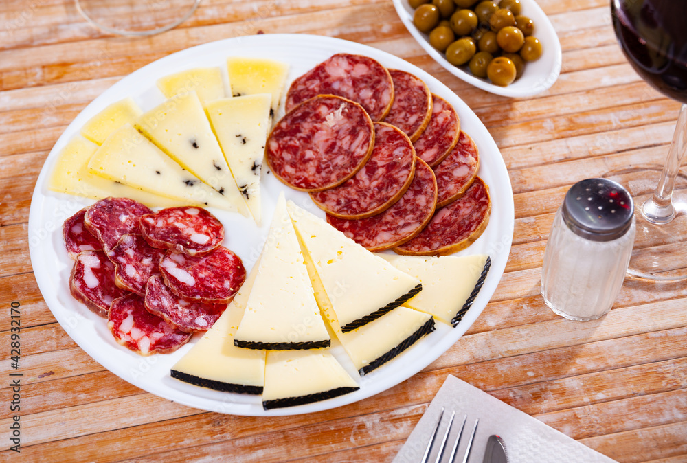 Traditional spanish snack tapas on a plate, selection of ham, salami and cheese