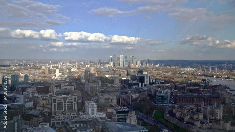 Aerial panning shot showing London Canary Wharf Cityscape with high rising buildings and River Thames Aerial panning shot showing London Canary Wharf Cityscape with high rising buildings and River Thames