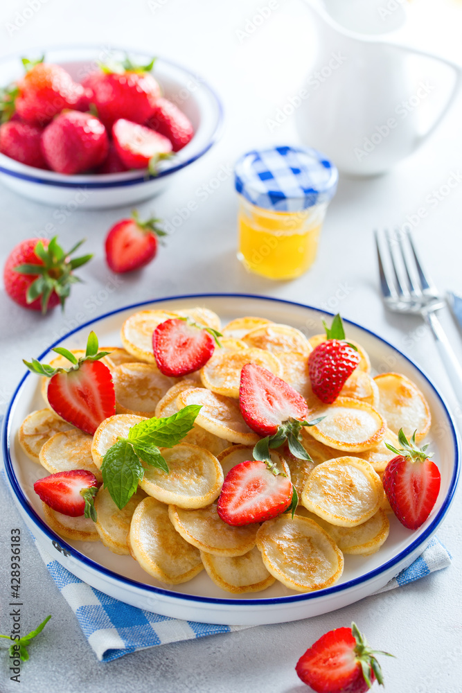 mini pancakes in a white plate with fresh strawberries, selective focus