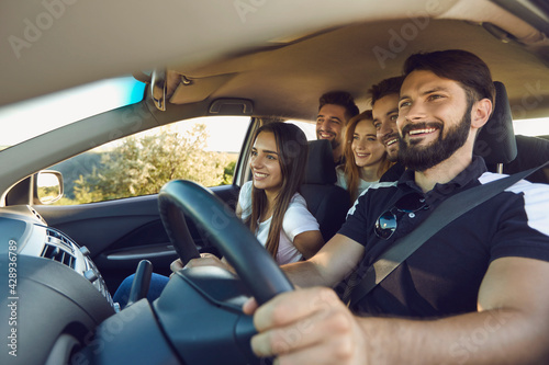 Group of young happy people having fun together and enjoying road trip sitting in car.
