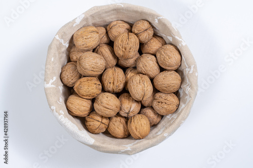 basket with whole walnuts on a white background, top view