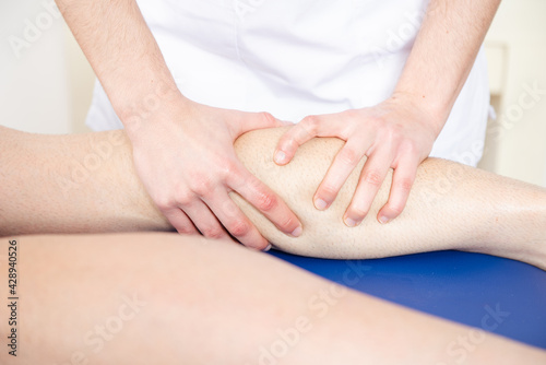The hands of a physiotherapist massaging the leg of an athlete.