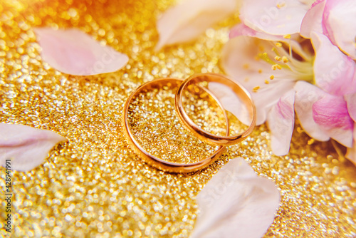 Gold wedding rings and Apple blossoms on a Golden background
 photo