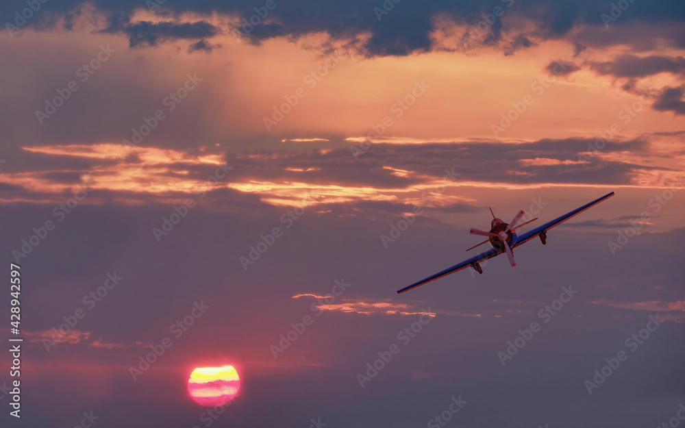 Beautiful colorful sunset landscape and vintage light propeller plane flying
