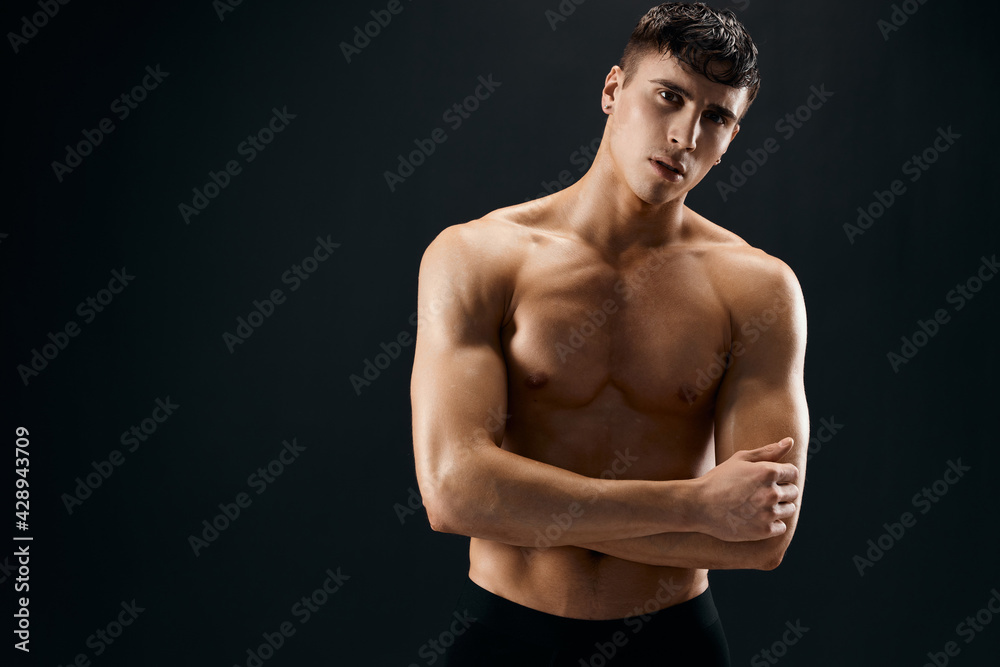 man with a muscular body posing against a dark background