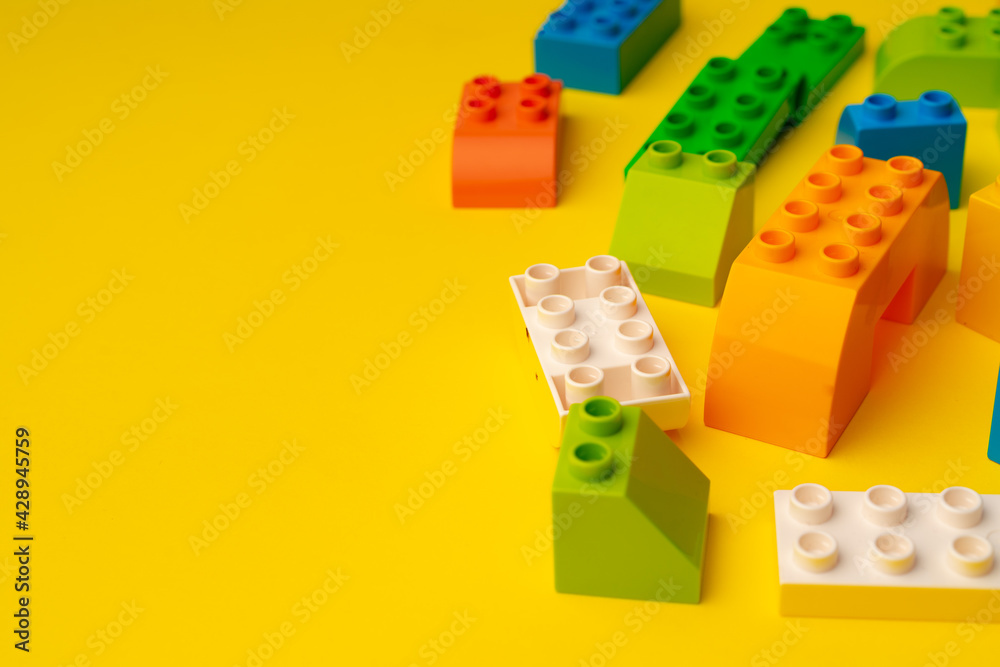 Obraz premium Kids toy constructor details scattered on yellow background