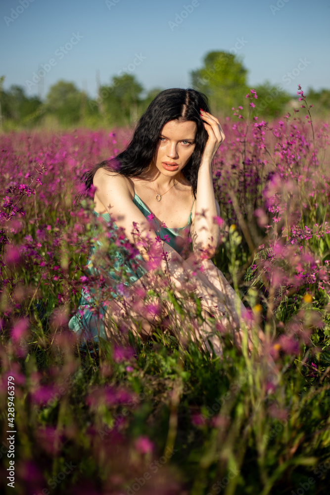 Girl in a turquoise dress in a blooming field Girl in a turquoise dress in a blooming field