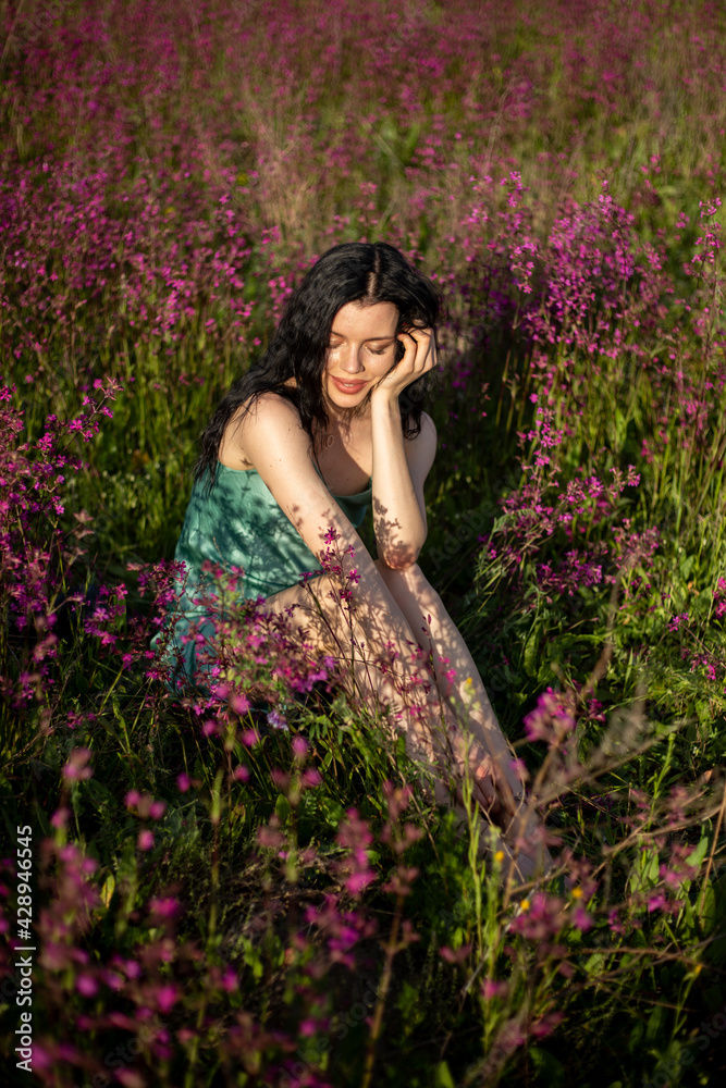 Girl in a turquoise dress in a blooming field Girl in a turquoise dress in a blooming field