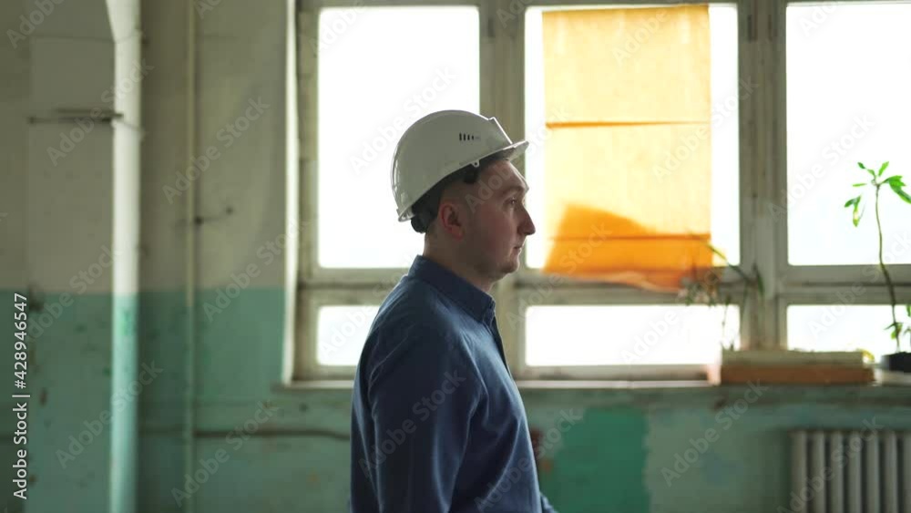 Engineer manager white protective helmet head. Walks around large hall columns supports construction site looks around checks work contractors evaluates investments. Demolition reconstruction building Engineer manager white protective helmet head. Walks around large hall columns supports construction site looks around checks work contractors evaluates investments. Demolition reconstruction building