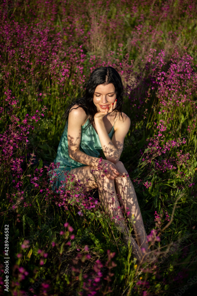 Girl in a turquoise dress in a blooming field Girl in a turquoise dress in a blooming field