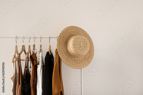 Women's fashion bright pastel clothes on clothing rack on white background. Minimalist fashion blog concept. photo