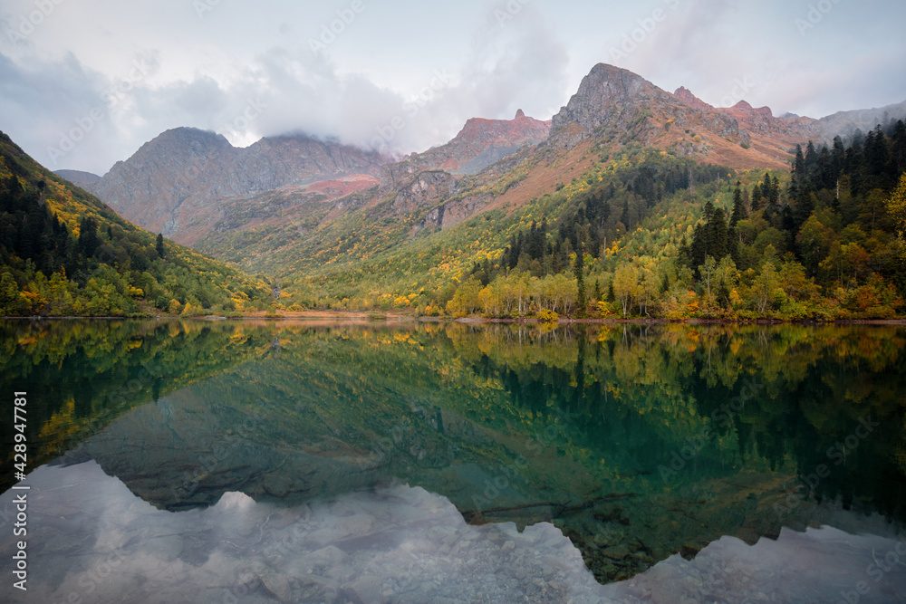 Beautiful autumn landscape, mountain lake, coniferous forest, mirror reflection. Russia, Kardyvach