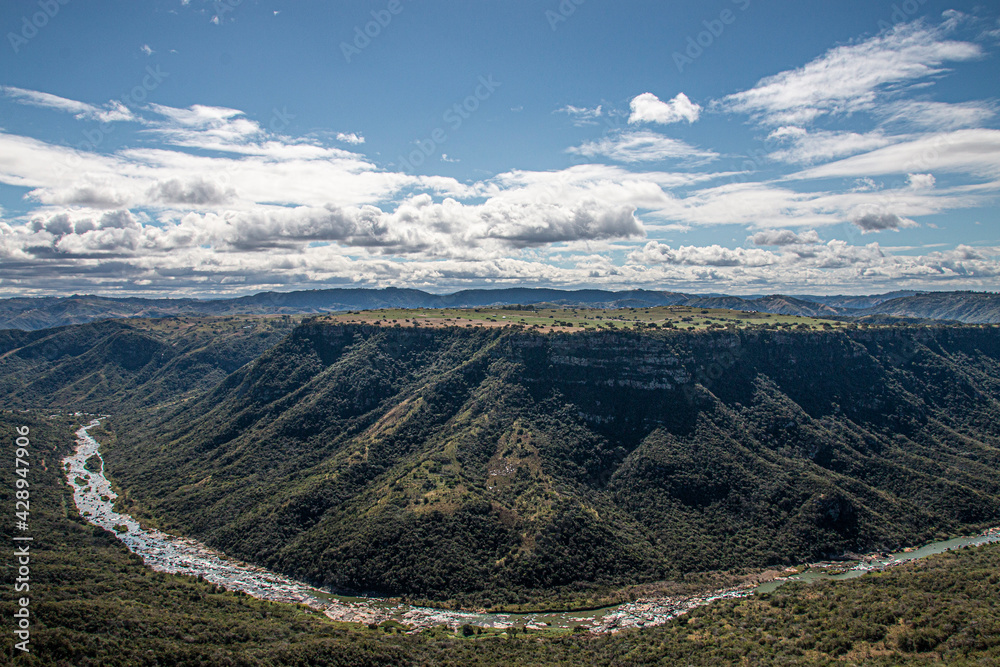 Fototapeta premium Meandering River Flowing Through Steep Tree-Lined Valley