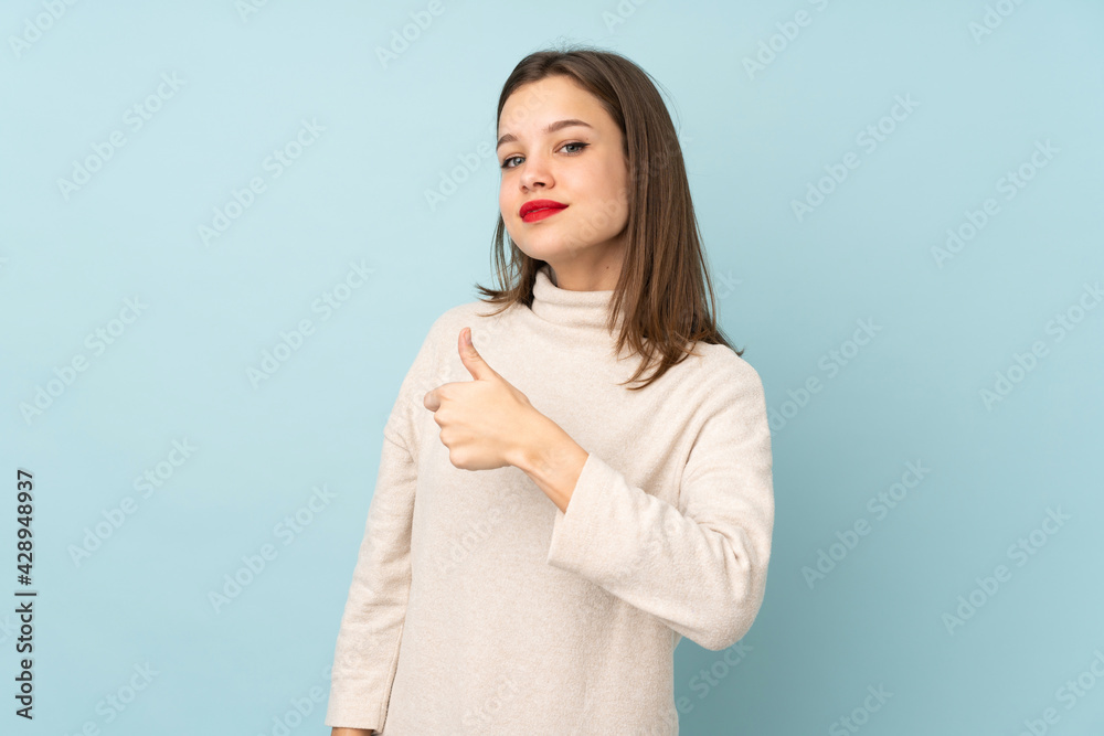 Teenager girl isolated on blue background giving a thumbs up gesture Teenager girl isolated on blue background giving a thumbs up gesture
