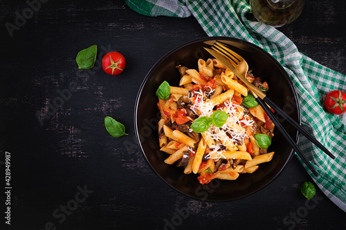 Pasta penne with eggplant. Pasta alla norma - traditional Italian food with eggplant, tomato, ricotta cheese and basil. Top view, overhead, copy space