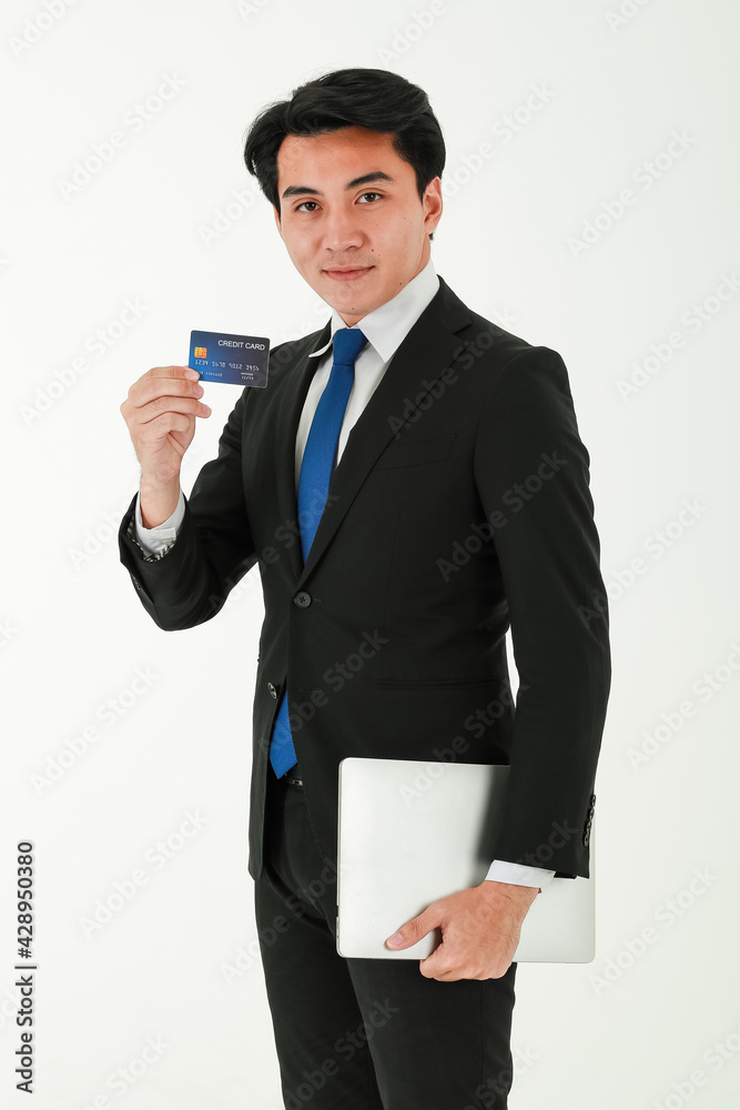 Portrait of happy young businessman in black suit having a credit card in one hand, smiling, standing over white background, looking at camera Portrait of happy young businessman in black suit having a credit card in one hand, smiling, standing over white background, looking at camera