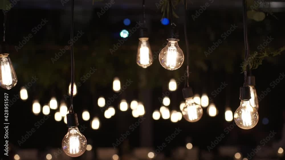 Light bulbs garland close up. Electric bulb shine hanging on wall as decoration wedding dinner.