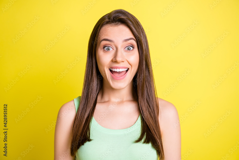 Photo of young happy positive smiling excited girl in green tank-top see big sale isolated on yellow color background Photo of young happy positive smiling excited girl in green tank-top see big sale isolated on yellow color background
