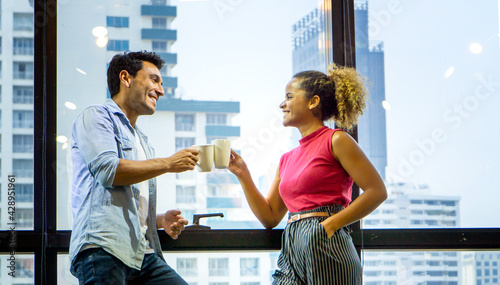 Happy young couple is drinking coffee and smiling while standing at the cafe