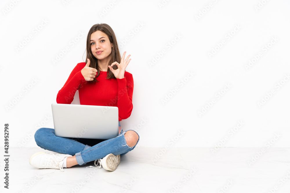 Tenaager girl working with pc isolated on white background showing ok sign and thumb up gesture Tenaager girl working with pc isolated on white background showing ok sign and thumb up gesture