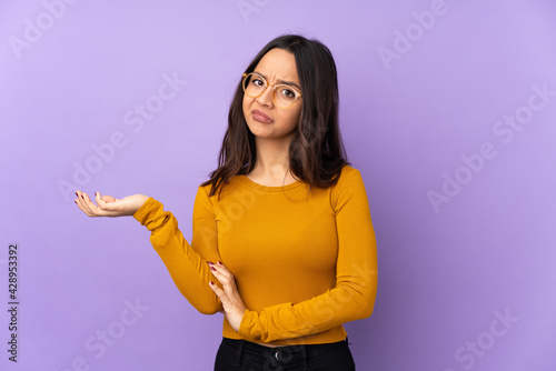 Young mixed race woman isolated on purple background unhappy for not understand something © luismolinero