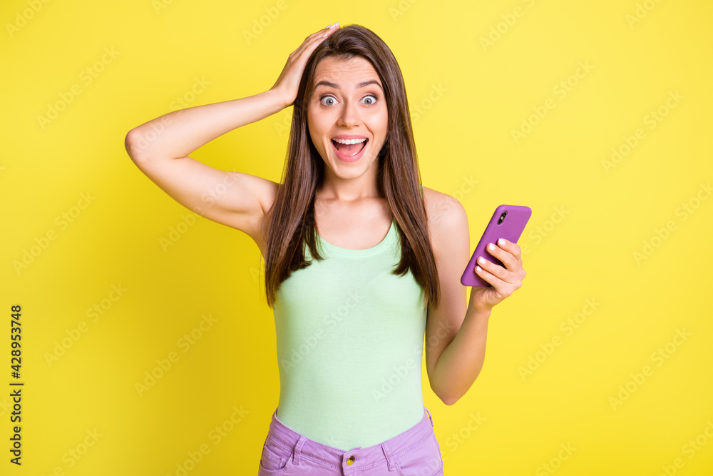 Photo of young beautiful lovely happy smiling amazed girl see good shocking news in phone isolated on yellow color background Photo of young beautiful lovely happy smiling amazed girl see good shocking news in phone isolated on yellow color background